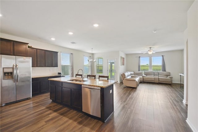 kitchen with sink, hanging light fixtures, dark hardwood / wood-style floors, an island with sink, and stainless steel appliances