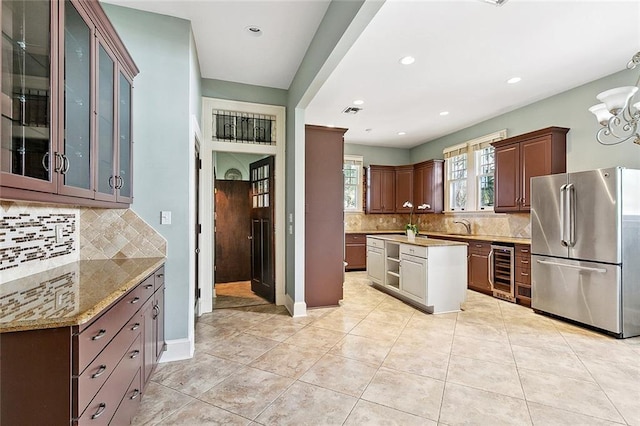 kitchen with sink, wine cooler, stainless steel fridge, light tile patterned floors, and tasteful backsplash