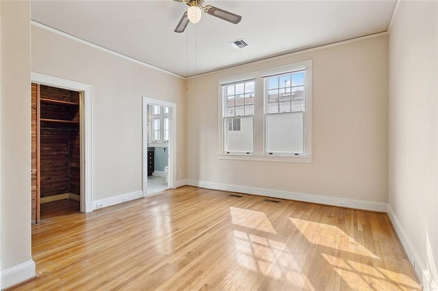 unfurnished bedroom with ensuite bath, ceiling fan, crown molding, a walk in closet, and hardwood / wood-style flooring