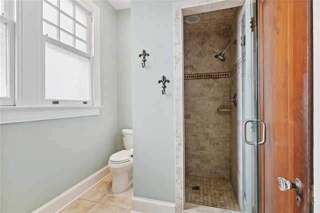 bathroom with tile patterned floors, toilet, and a shower with shower door