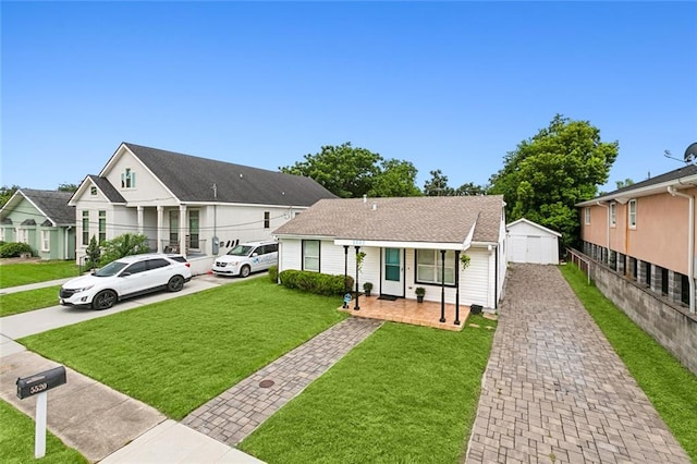 view of front of property featuring an outbuilding, decorative driveway, fence, a residential view, and a front lawn