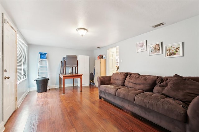 living room with baseboards, visible vents, and wood finished floors