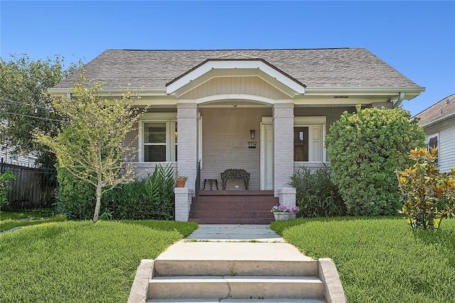 bungalow-style home featuring covered porch and a front lawn