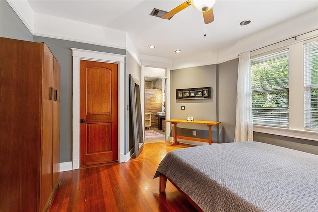 bedroom with ensuite bath, ceiling fan, and hardwood / wood-style flooring