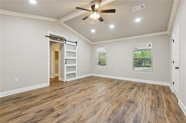 unfurnished bedroom with lofted ceiling with beams, wood-type flooring, ceiling fan, crown molding, and a barn door