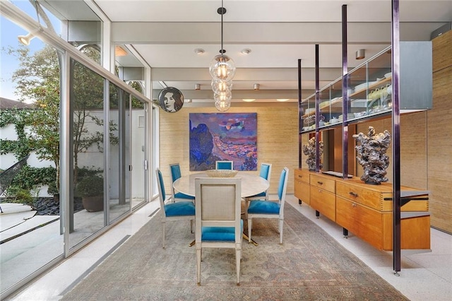 dining room featuring floor to ceiling windows, a wealth of natural light, and wooden walls