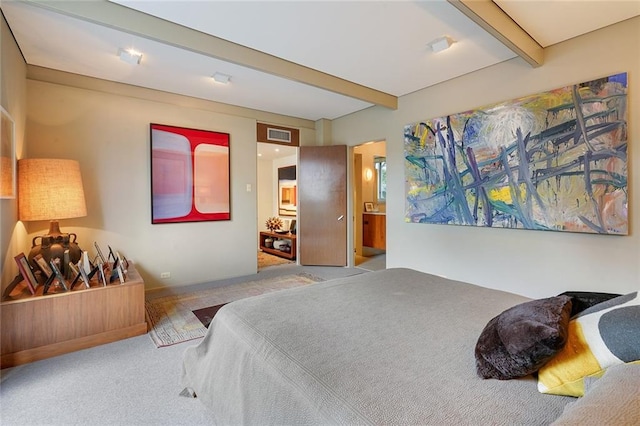 bedroom featuring beamed ceiling, light carpet, and ensuite bath