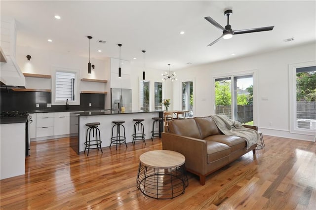 living room featuring light hardwood / wood-style floors and ceiling fan with notable chandelier