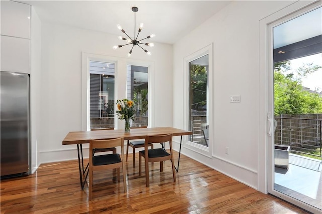 dining area featuring plenty of natural light, wood-type flooring, and a notable chandelier