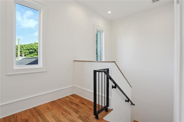 stairway featuring a wealth of natural light and wood-type flooring