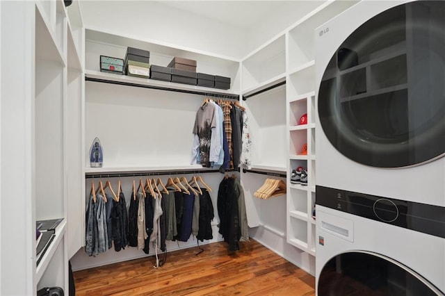 spacious closet featuring hardwood / wood-style floors and stacked washer / dryer