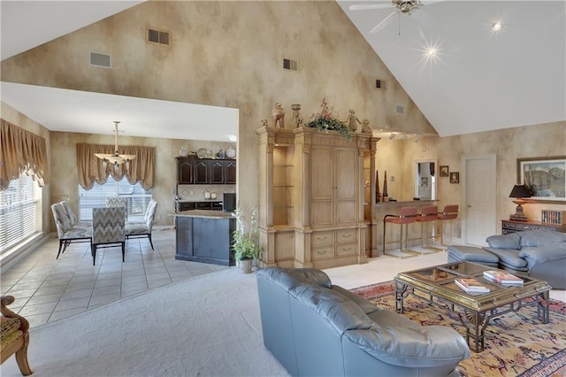 carpeted living room with ceiling fan with notable chandelier and high vaulted ceiling