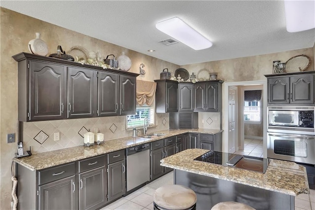 kitchen with appliances with stainless steel finishes, a center island, sink, and light tile patterned floors