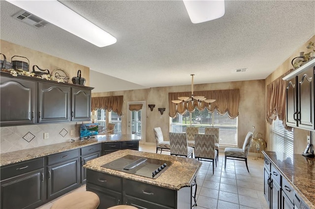 kitchen with hanging light fixtures, a kitchen island, a healthy amount of sunlight, and black electric cooktop