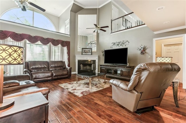 living room with a tile fireplace, crown molding, hardwood / wood-style floors, and ceiling fan