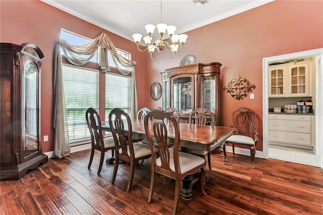 dining area featuring dark wood-type flooring, ornamental molding, and a chandelier