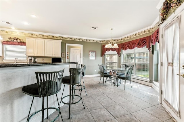 kitchen with crown molding, hanging light fixtures, light tile patterned floors, a kitchen breakfast bar, and a notable chandelier