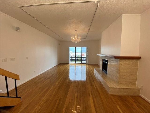 unfurnished living room with a chandelier, a textured ceiling, and dark hardwood / wood-style floors