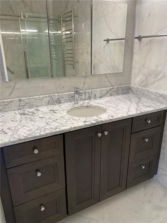 bathroom featuring tile flooring, tile walls, radiator, and vanity