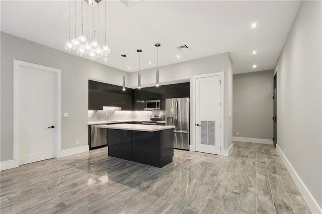 kitchen featuring appliances with stainless steel finishes, a center island, pendant lighting, and backsplash