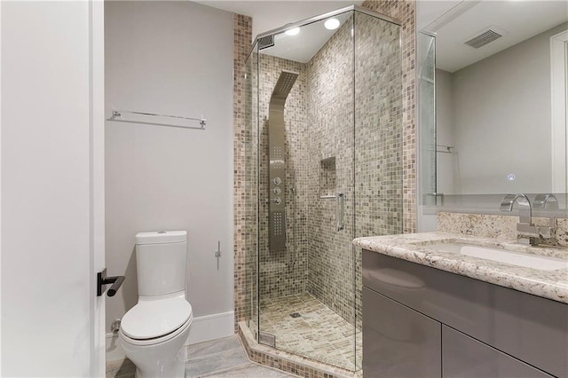 bathroom with tile patterned floors, vanity, toilet, and a shower with shower door