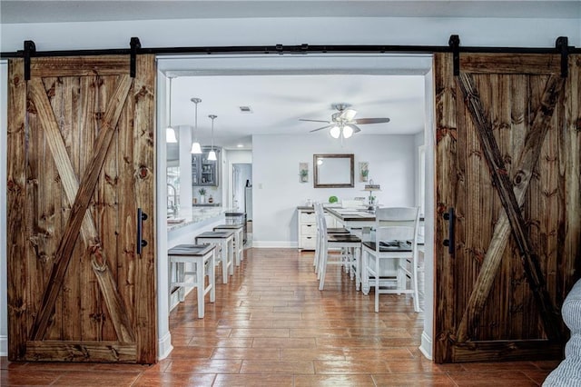 interior space with a barn door, ceiling fan, and hardwood / wood-style flooring