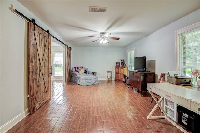 living room with hardwood / wood-style floors, a barn door, and ceiling fan