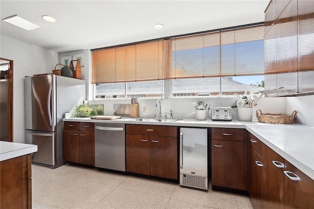 kitchen featuring appliances with stainless steel finishes, sink, a wealth of natural light, and dark brown cabinets