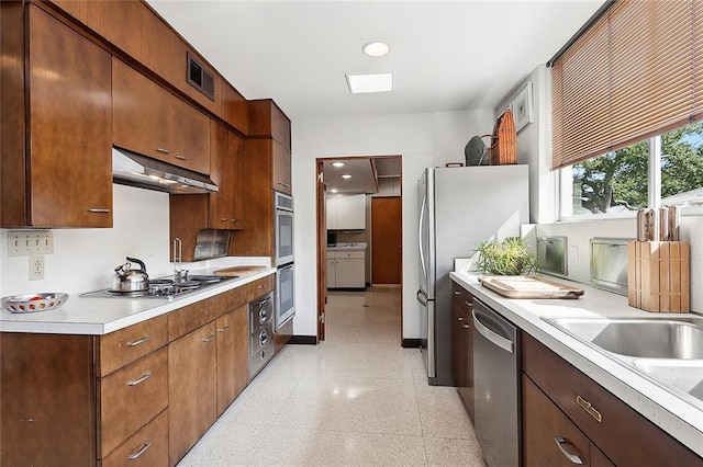 kitchen with appliances with stainless steel finishes, sink, and exhaust hood