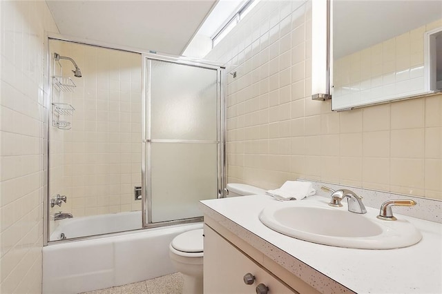 full bathroom with enclosed tub / shower combo, vanity, toilet, and tile walls