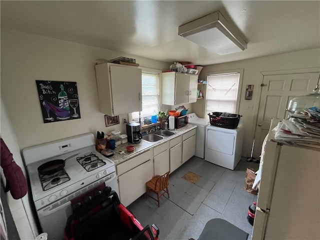 kitchen with electric stove, washer and dryer, light tile flooring, sink, and white cabinetry