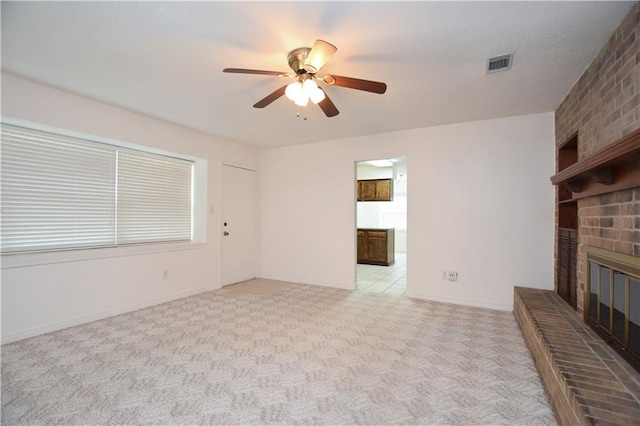 unfurnished living room featuring brick wall, ceiling fan, light carpet, and a brick fireplace