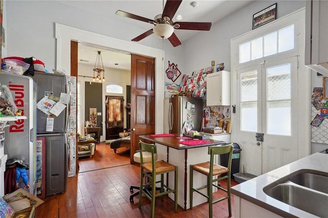 kitchen featuring white cabinetry, stainless steel refrigerator, a kitchen breakfast bar, sink, and dark hardwood / wood-style floors