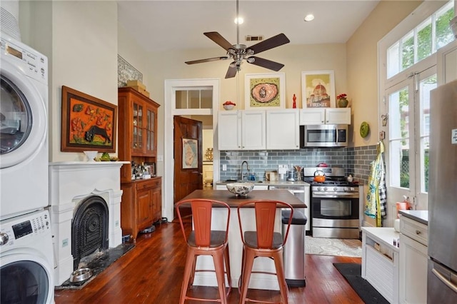 kitchen featuring a center island, appliances with stainless steel finishes, a kitchen breakfast bar, stacked washer and dryer, and backsplash