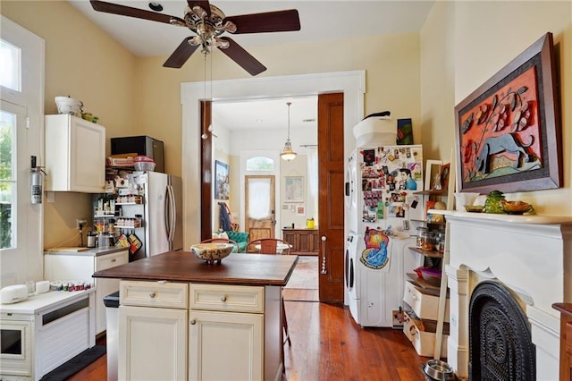 kitchen featuring white refrigerator, white cabinets, hanging light fixtures, and dark hardwood / wood-style flooring