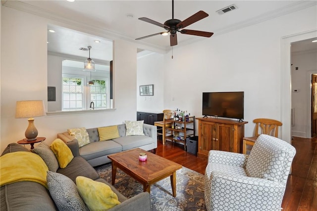 living room with crown molding, dark wood-type flooring, and ceiling fan