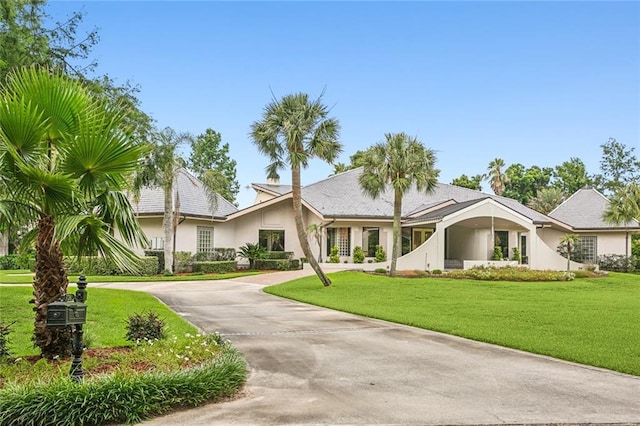 view of front facade with stucco siding, a front lawn, and driveway