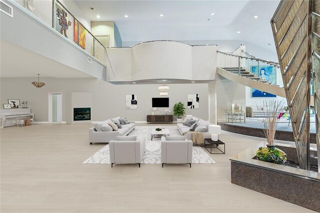 living room featuring visible vents, a towering ceiling, and wood finished floors