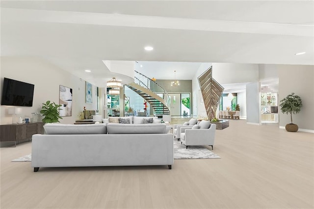 living area with recessed lighting, stairway, an inviting chandelier, light wood finished floors, and baseboards