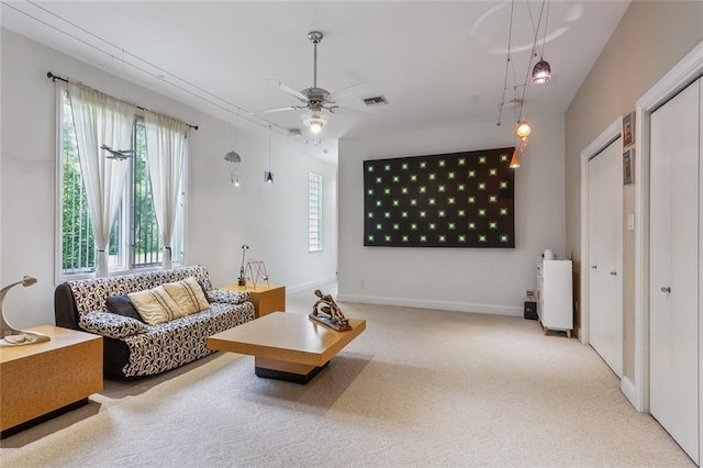 carpeted living area featuring visible vents, plenty of natural light, baseboards, and ceiling fan