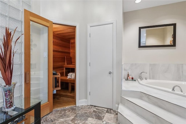 bathroom with marble finish floor and a garden tub