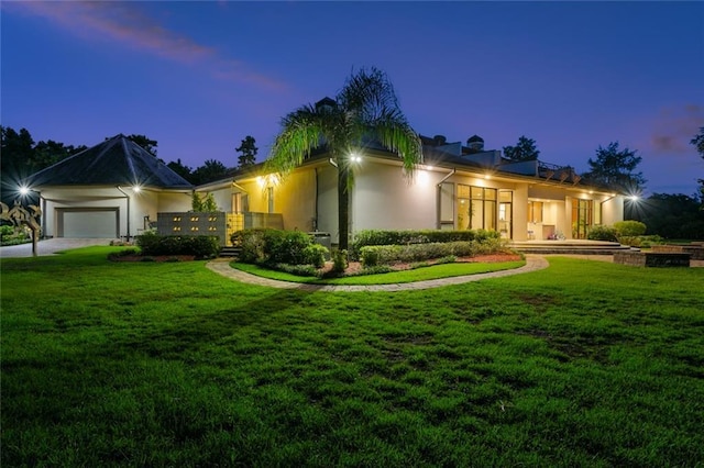 view of front facade featuring an attached garage, a yard, driveway, and stucco siding