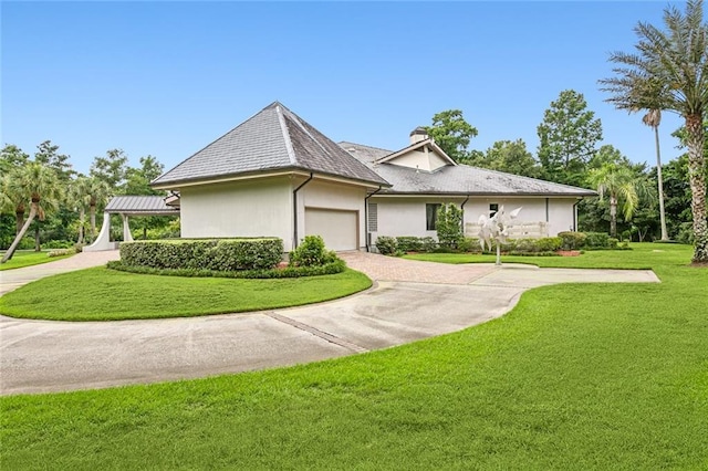 view of front of property with stucco siding, a front lawn, decorative driveway, a garage, and a chimney