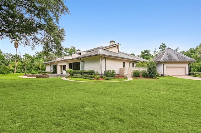 view of front facade featuring stucco siding, driveway, a front lawn, an attached garage, and a chimney