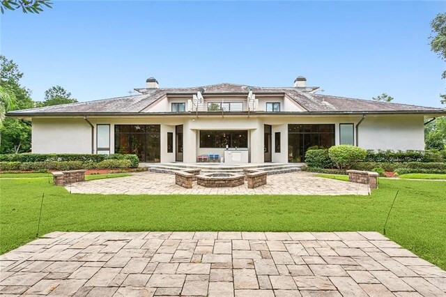 back of property with stucco siding, a chimney, and a patio