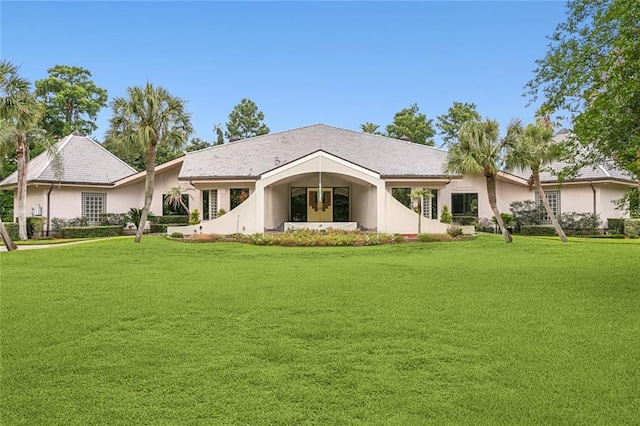 back of property featuring stucco siding and a lawn