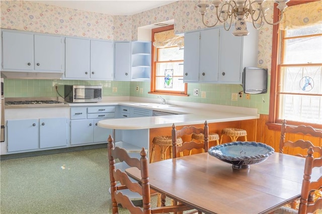 kitchen featuring backsplash, plenty of natural light, kitchen peninsula, and appliances with stainless steel finishes