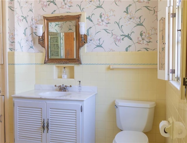 bathroom featuring vanity, toilet, and tile walls