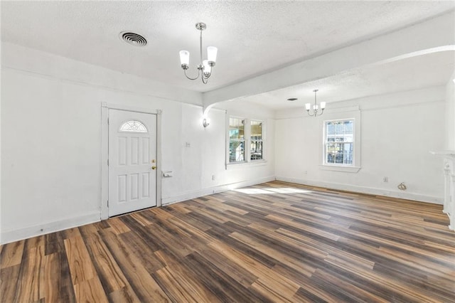 foyer featuring an inviting chandelier, a textured ceiling, and dark wood-type flooring