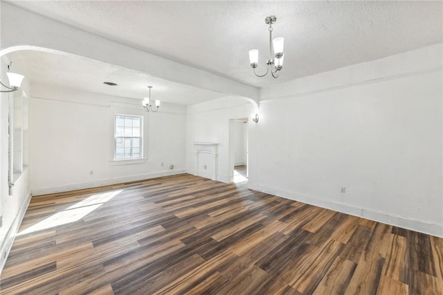 spare room with dark hardwood / wood-style floors, a textured ceiling, and an inviting chandelier